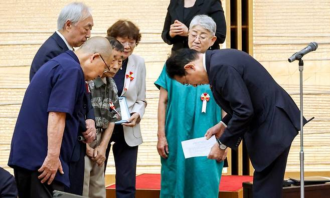 기시다 후미오 일본 총리(오른쪽)가 17일 도쿄 총리관저에서 강제 불임수술 피해자들과 만나 사죄를 표명하며 고개를 숙이고 있다.  아사히신문 제공