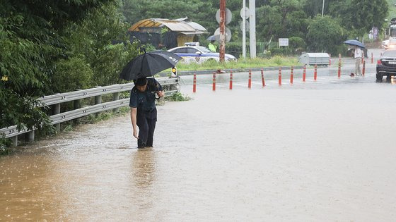 경기북부에 호우경보가 내린 17일 오전 경기 파주시 문산에서 도로가 물에 잠긴 모습. 시민들은 차에서 내려 걸어서 지하철역으로 향하기도 했다. 연합뉴스