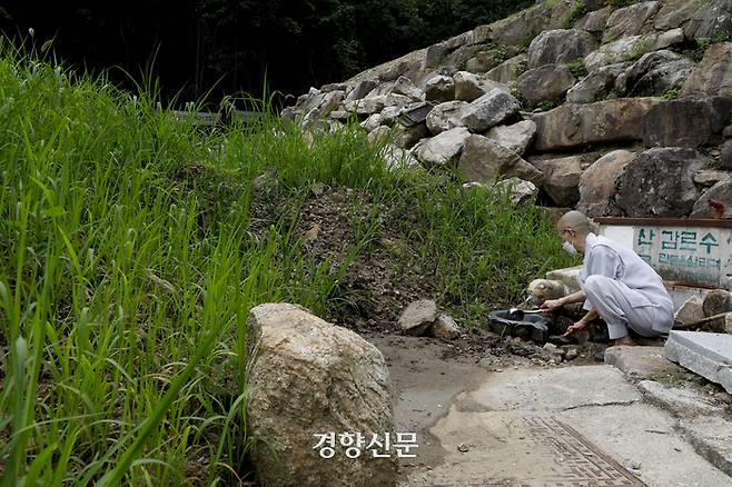 법륜사 주지 혜륜 스님이 지난 15일 산사태가 덮쳤던 대웅전 주변 샘터에서 물을 뜨고 있다.  문재원 기자