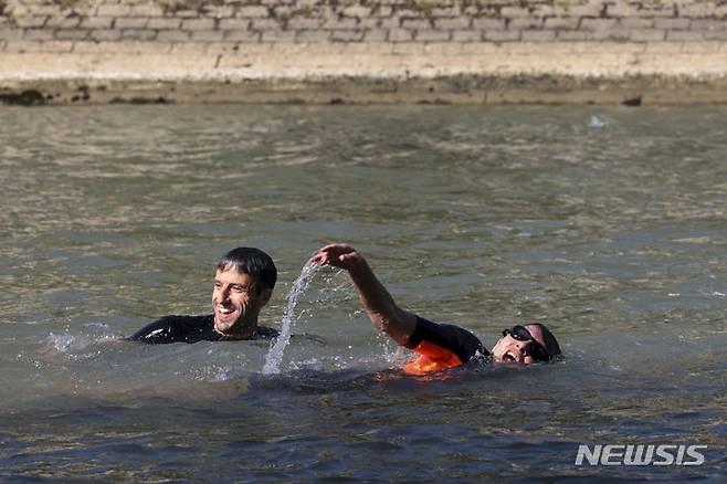 Paris Mayor Anne Hidalgo and Tony Estanguet, President of the Paris 2024 Olympic and Paralympic Games Organizing Committee, swim in the Seine river, Wednesday, July 17, 2024 in Paris. After months of anticipation, Paris Mayor Anne Hidalgo took a dip in the Seine River on Wednesday, fulfilling a promise she made months ago to show the river is clean enough to host open-swimming competitions during the 2024 Olympics — and the opening ceremony on the river nine days away.(Joel Saget, Pool via AP)