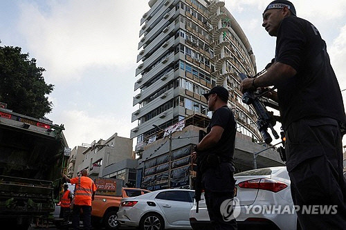 19일(현지시간) 새벽 드론 공격으로 폭발이 발생한 이스라엘 텔아비브의 한 아파트 앞을 경찰관들이 지키고 있다. [로이터=연합뉴스]