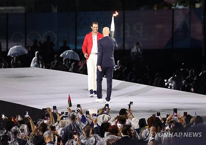 라파엘 나달에게 개회식 성화 전달하는 지네딘 지단 (파리=연합뉴스) 황광모 기자 = 지네딘 지단이 26일(현지시간) 프랑스 파리 트로카데로 광장에서 열린 2024 파리 올림픽 개회식에서 성화를 다음 주자인 라파엘 나달에게 전달하고 있다.  2024.7.27 hkmpooh@yna.co.kr