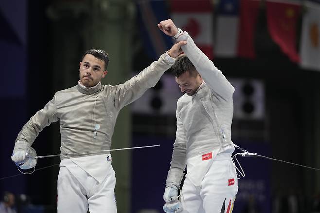 Germany's Matyas Szabo, right, celebrates at the end of the men's individual Sabre round of 16 competition against France's Sebastien Patrice during the 2024 Summer Olympics at the Grand Palais, Saturday, July 27, 2024, in Paris, France. (AP Photo/Andrew Medichini) 승자의 손을 들어주는 세바스티앵 파트리스[AP=연합뉴스]