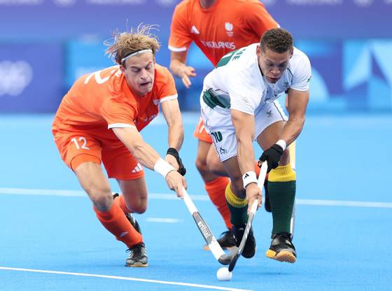 Justen Blok of the Netherlands, left, competes with Keenan Horne of South Africa during the men's pool of hockey in Paris, France on Saturday. [XINHUA/YONHAP]
