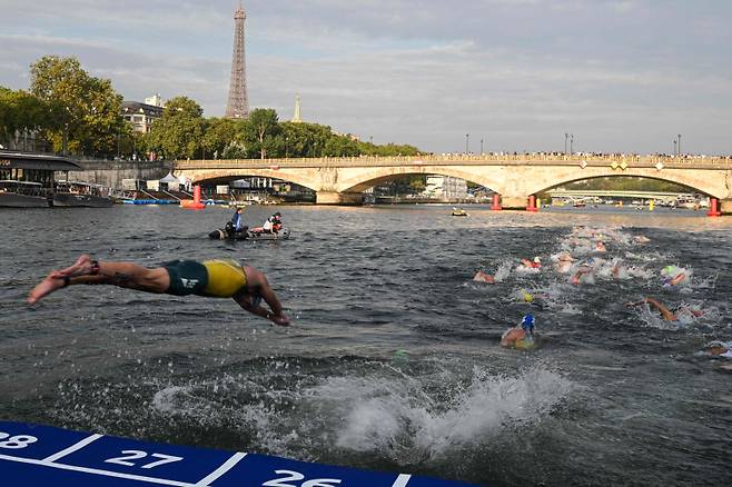 <yonhap photo-2469=""> (FILES) Triathlon athlete dives in the Seine river with The Eiffel Tower in the background during the men's 2023 World Triathlon Olympic Games Test Event in Paris, on August 18, 2023. From August 17 to 20, 2023, Paris 2024 is organising four triathlon events to test several arrangements, such as the sports operations, one year before the Paris 2024 Olympic and Paralympic Games. The swim familiarisation event follows the cancellation on August 6 of the pre-Olympics test swimming competition due to excessive pollution which forced organisers to cancel the pre-Olympics event. (Photo by Bertrand GUAY / AFP)/2024-07-22 12:11:52/ <저작권자 ⓒ 1980-2024 ㈜연합뉴스. 무단 전재 재배포 금지, AI 학습 및 활용 금지></yonhap>