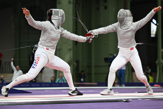 Korea's Choi Se-bin, left, competes against Japan's Misaki Emura in the women's sabre individual round of 16 during the Paris Olympics at the Grand Palais in Paris on Monday.  [AFP/YONHAP]