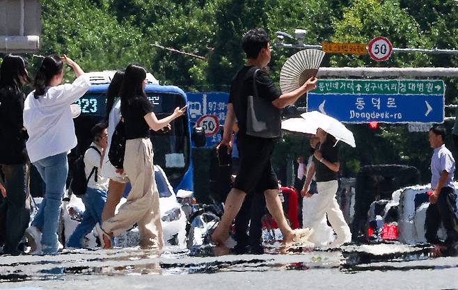 폭염 경보가 발효 중인 29일 대구 중구 공평네거리에서 시민들이 지열로 인한 아지랑이가 피어오르는 도로를 지나가고 있다. /연합뉴스