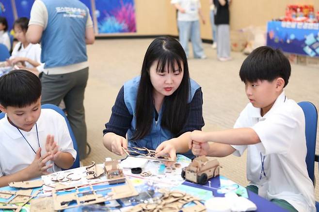 포스코퓨처엠 직원이 30일 포항 포스코 본사 대강당에서 열린'푸른꿈 환경캠프'에 멘토로나서 어린이와 함께 전기차 모형을 제작하고 있다. ⓒ포스코퓨처엠