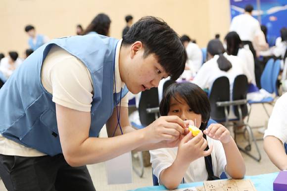 포스코퓨처엠 직원이 30일 포항 포스코 본사 대강당에서 열린 '푸른꿈 환경캠프'에 멘토로 나서 어린이와 함께 전기차 모형을 제작하고 있다. [사진=포스코퓨처엠 제공]