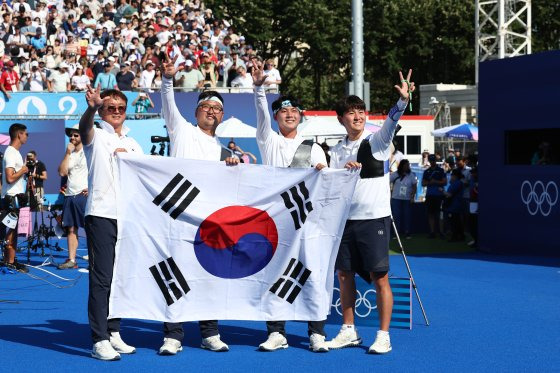 한국 양궁 남자대표팀이 29일(현지시간) 프랑스 파리의 레쟁발리드에서 열린 2024 파리 올림픽 단체전 결승에서 개최국 프랑스를 꺾고 금메달을 차지했다. 남자대표팀의 박성수 감독과 김우진·이우석·김제덕 선수(왼쪽부터)가 경기 후 태극기를 들고 축하 세리머니를 하고 있다. [연합뉴스]