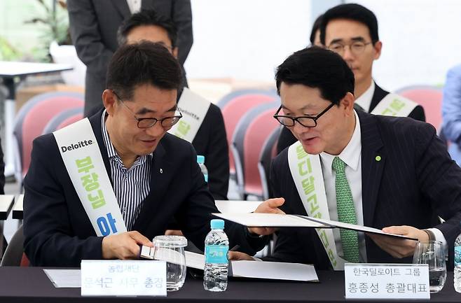 문석근 농협재단 사무총장(왼쪽)과 홍종성 한국 딜로이트그룹 총괄대표가 31일 오전 서울 영등포구 IFC 광장에서 열린 농협-한국 딜로이트 그룹 쌀 기부를 위한 기부 약정 체결식에 참석해 서명한 약정서를 교환하고 있다. 최혁 기자