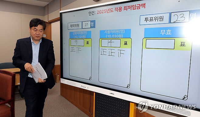 지난 12일 새벽 이인재 최저임금위원장이 정부세종청사에서 열린 제11차 전원회의에서 노사 양측 최종안의 표결을 거쳐 내년 최저임금을 시간당 1만30원으로 결정한 뒤 퇴장하고 있다. [사진=연합뉴스]