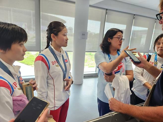 북한 선수보다 더 많은 말을 한 북한 관계자 (파리=연합뉴스) 하남직 기자 = 31일(한국시간) 프랑스 파리 아쿠아틱센터에서 열린 파리 올림픽 다이빙 여자 싱크로 10ｍ 플랫폼에서 2위를 찾지한 김미래(가운데)와 조진미(왼쪽)가 공동취재구역에서 외신 기자의 인터뷰에 응하고 있다. 하지만, 실제 대답은 북한 관계자(오른쪽 두 번째)가 더 많이 했다.