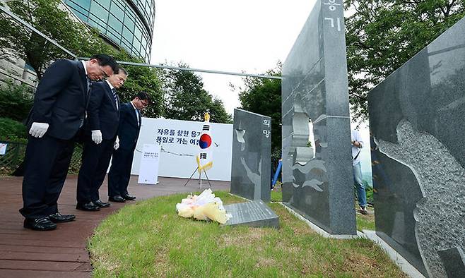 김영호 통일부 장관이 1일 경기 파주시 탄현면 오두산전망대 뒤뜰에서 열린 북한이탈주민의 날 기념 조형물 제막식에서 헌화하고 묵념을 하고 있다. 왼쪽부터 태영호 민주평화통일자문회의 사무처장, 김 장관, 지성호 전 국회의원. 파주=뉴시스