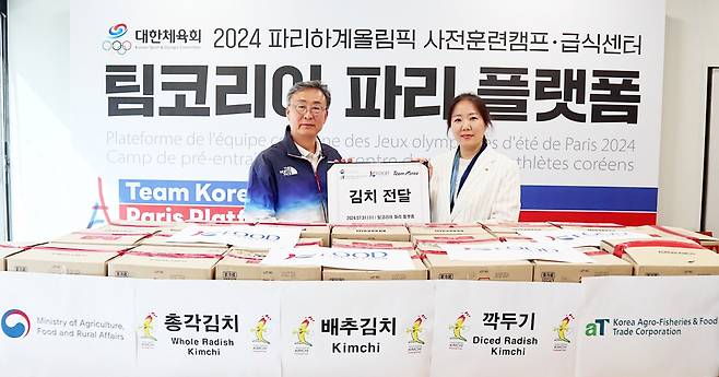 The Korea Agro-Fisheries & Food Trade Corp.’s Paris division chief Nam Sang-hui (right) and Chung Dong-kook, vice chief of the National Training Center under the Korean Sport & Olympic Committee, pose for a photo at a kimchi handover ceremony at the Team Korea Paris Platform in Fontainebleau, outside Paris, on July 31. (aT)