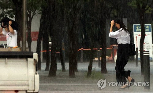 무더위가 계속되는 5일 서울 시내에서 한 시민이 소나기를 피하고 있다. [연합뉴스]