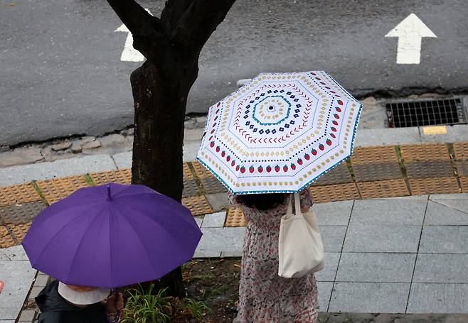 전국 대부분 지역에 폭염경보가 발효된 5일 광주 서구 치평동에서 한 시민이 내리는 소나기에 우산을 쓰고 걷고 있다. [연합]