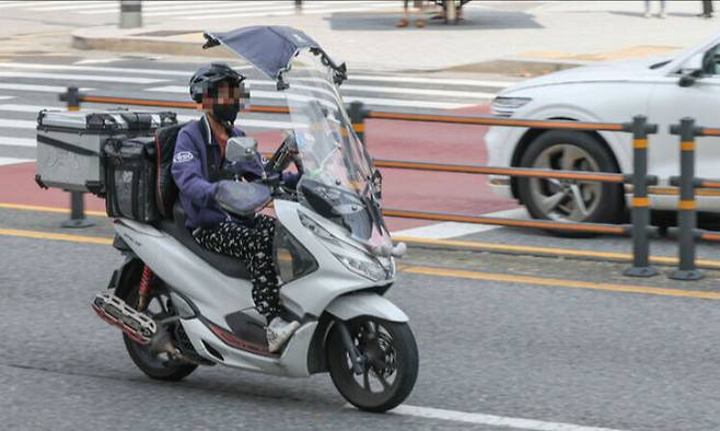 서울 최고온도가 35도에 달해 무더운 날씨를 보인 4일 서울 관악구의 한 도로에서 배달 라이더가 차양막으로 햇빛을 가리며 배달 업무를 하고 있다. 최상수 기자