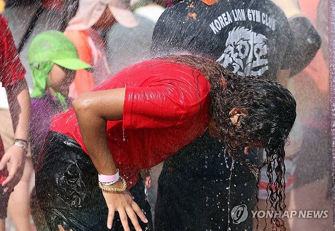 '날씨가 더워요' (화천=연합뉴스) 이상학 기자 = 강원 화천군 사내면 사창리에서 토마토축제가 한창인 가운데 3일 오후 '황금반지를 찾아라' 이벤트에 참가한 외국인 관광객이 간이샤워장에서 샤워를 하며 더위를 잊고 있다. 2024.8.3 hak@yna.co.kr