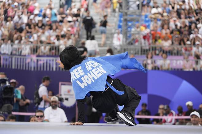 난민 대표팀의 마니자 탈라시가 9일(현지시각) 프랑스 파리 콩코르드 광장에서 열린 2024 파리올림픽 브레이킹 비걸 조별예선에서 ‘아프간 여성들에 자유를’이라는 문구를 펼쳐 보이고 있다. 파리/AP 연합뉴스