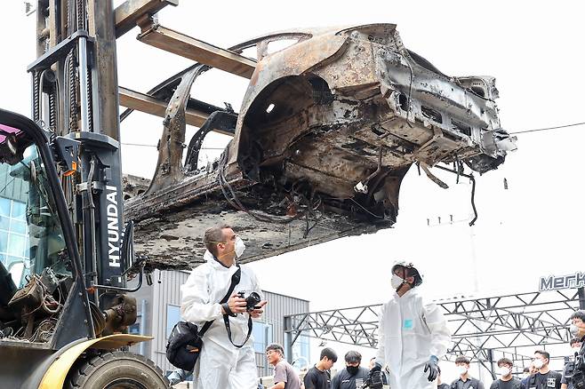 The burnt Mercedes EQE sedan is transferred for investigation in Incheon on Thursday. The EV explosion injured 23 people and damaged around 880 vehicles in the parking garage. Some 500 households have suffered from electricity outrages for a week. [YONHAP]