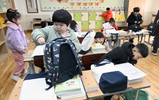 인천의 한 초등학교에서 입학식을 마친 1학년 신입생들이 교과서를 가방에 담고 있다. 경기일보DB