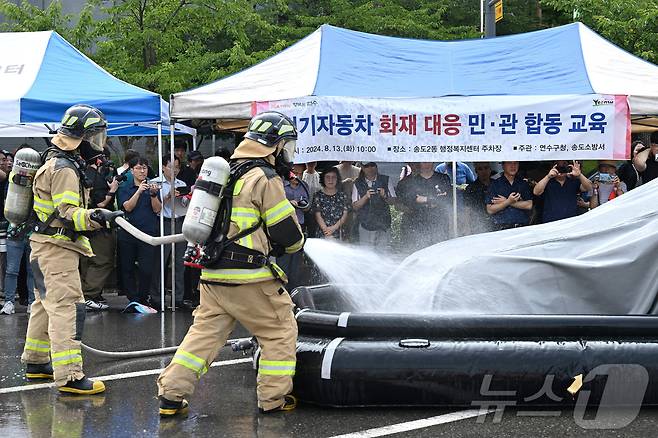 최근 잇단 화재로 이른바 '전기차 공포증(포비아)'이 확산하는 가운데 13일 인천시 연수구 송도 2동 행정복지센터 주차장에서 열린 전기자동차 화재대응 민·관 합동 교육에서 소방관들이 질식소화포와 전기차 수조탱크를 이용한 전기차 화재 진압 모의 시연을 하고 있다.(중부일보 제공)2020.8.13/뉴스1