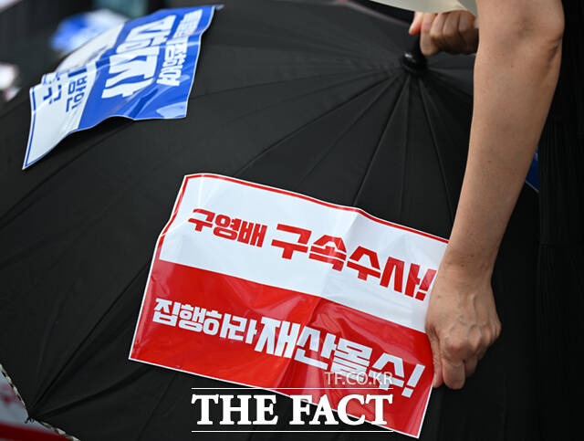 13일 서울 강남구 신사동 티몬 본사 앞에서 열린 티메프 피해자 연합 우산 집회에 모인 한 참가자가 우산에 '구영배 구속수사, 집행하라 재산몰수'가 적힌 스티커를 붙이고 있다. /신사동=이새롬 기자