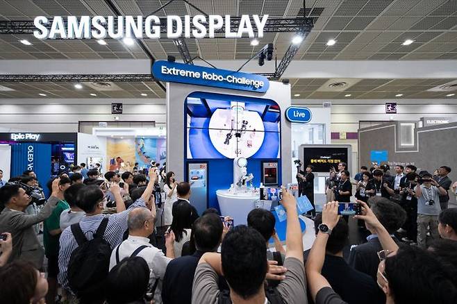 'K-디스플레이 2024'에 참가한 삼성디스플레이 부스에서 관람객들이 폴더블 내구성을 테스트하는 로봇쇼를 관람하는 모습ⓒ삼성디스플레이