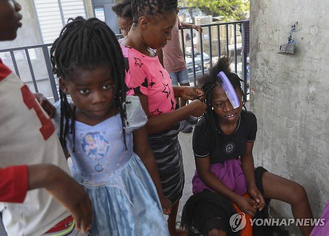 난민 센터로 변한 학교에 모인 아이들 (포르토프랭스 AP=연합뉴스) 13일(현지시간) 아이티 포르토프랭스 내 난민 센터로 이용되는 학교에서 한 여성이 소녀의 머리를 땋아주고 있다. 2024.8.14