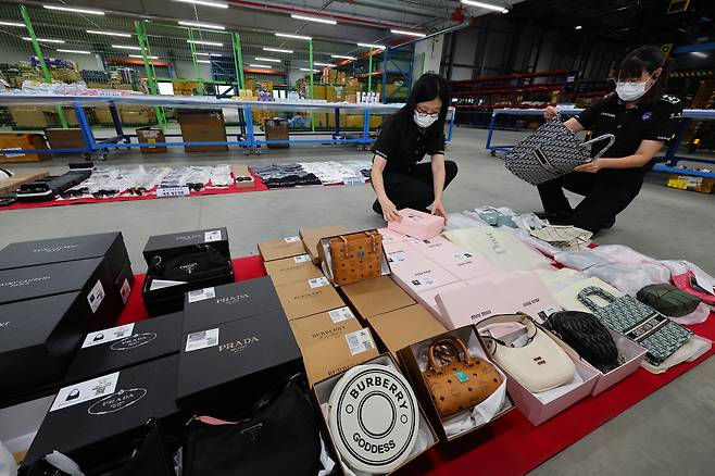 Customs officials examine the seized counterfeit items of luxury brand products at the Officials of the Incheon Main Customs in Incheon on July 23. (Yonhap)