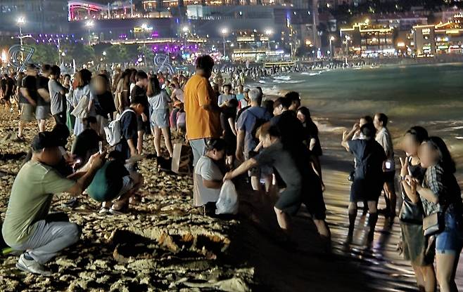 People gather at Haeundae Beach in Busan to cool off on Saturday. [NEWS1]