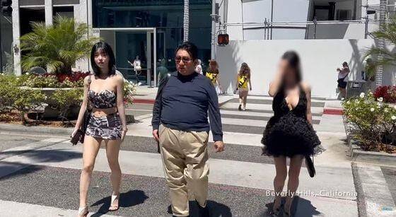 HYBE Chairman Bang Si-hyuk (center) walks with AfreecaTV streamer Seyeon (left), in this video grab from the YouTube channel I Am Walking. /News1