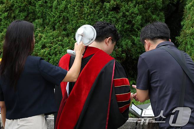 21일 서울 동대문구 경희대학교에서 열린 2023학년도 후기 학위수여식에서 한 시민이 졸업생에게 선풍기 바람을 쐬어주고 있다. 2024.8.21/뉴스1 ⓒ News1 신웅수 기자