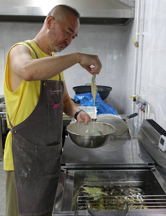 ‘자연 담은 고기밥상’의 김학묵 대표가 산나물을 튀기고 있다. [사진 이택희]