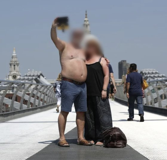 영국 런던의 밀레니엄브리지에서 웃통을 벗은 남성(왼쪽)이 일행과 기념 촬영을 하고 있다. 사진 더 선 홈페이지 캡처