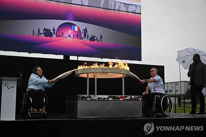 2024 파리 패럴림픽 성화 채화 (에일즈베리[영국] AFP=연합뉴스) 영국의 헬렌 레인스퍼드(왼쪽)와 그레고르 이완이 24일(현지시간) 영국 스토크맨더빌에서 2024 파리 패럴림픽 성화를 채화하고 있다.