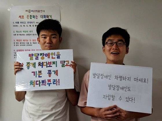 (왼쪽부터) 발달장애인 남태준(25)씨와 이종원(33)씨가 자신의 손글씨를 본 뜬 글꼴이 적힌 피켓을 들고 있다. 각각 "발달장애인을 안 좋게 쳐다보지 말고, 기분 좋게 쳐다봐주라!", "발달장애인 차별하지 마세요! 발달장애인도 자립할 수 있다!"라고 적었다. 이영근 기자