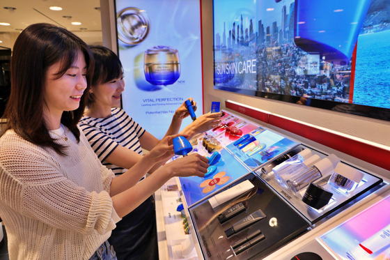 Customers test sunscreen products at a department store in Korea in June. [LOTTE DEPARTMENT STORE]