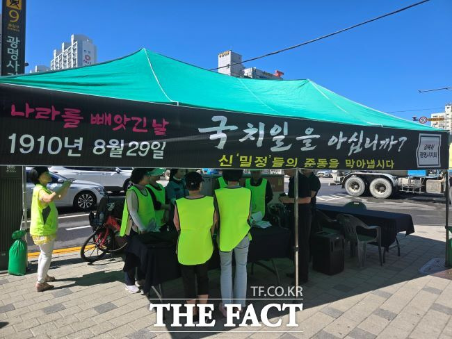 29일 경기 광명역사거리 일대에서 광복회 광명시지회 회원들이 "신 ‘밀정’들의 준동을 막아냅시다"라고 쓰인 그늘막 아래서 시민들에게 경술국치 유인물과 흰죽을 나누고 있다./광명시