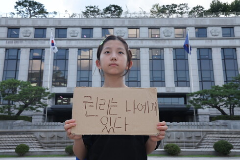 기후소송 헌법소원 선고 전날인 28일 헌법재판소 앞에서 청구인 중 한명인 한제아양이 손팻말을 들고 서 있다. 김영원 기자