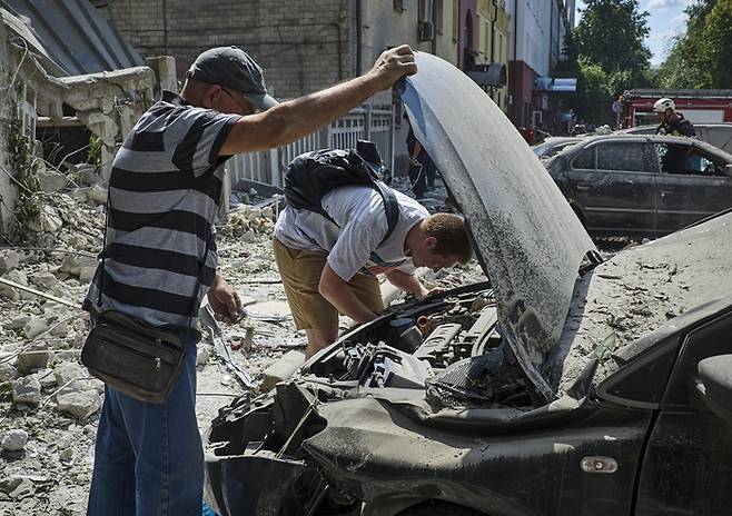 6일(현지시간) 우크라이나 하르키우 시내에서 현지 주민들이 러시아의 로켓 공격에 파괴된 차량을 살펴보고 있다. 이날 러시아의 로켓 공격으로 최소 8명의 주민이 부상했다. 2024.08.07  [사진 = EPA=연합뉴스]