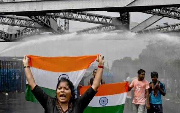 인도 서벵골주(州)에서 여성 의사가 잔혹하게 강간·살해당한 사건과 관련해 27일(현지시간) 거리로 나온 시위대의 모습. 국기를 든 시위대 뒤로 경찰이 쏜 물대포가 보인다. AFP 연합뉴스