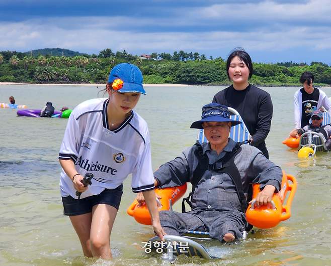 표선고등학교 인권동아리 ‘이끼’ 학생들이 지난 11일 표선해수욕장에서 송윤호씨(75)와 현석헌씨(57)가 탄 수중 휠체어를 끌어주고 있다. 강은 기자