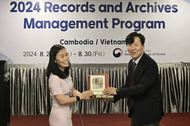 최유균 국가기록원 기록관리교육센터장(오른쪽)이 26일 오후(현지시간) 캄보디아 기록원 인근 호텔에서 열린 '베트남-캄보디아 국제 기록관리 연수과정 입교식'에 참석해 교육생 대표와 선물을 교환하고 기념촬영을 하고 있다. <행정안전부 제공>