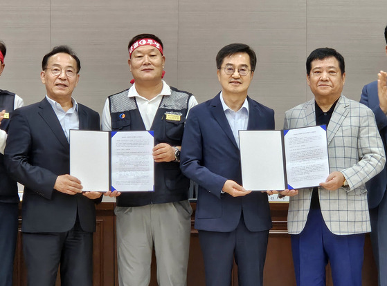 Gyeonggi Gov. Kim Dong-yeon, second from right, poses with representatives of unionized bus drivers and bus company owners in Suwon, Gyeonggi, on Wednesday, after reaching a last-minute wage hike deal to avert a general strike. [YONHAP]