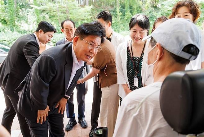 박강수 마포구청장이 전동휠체어를 탄 장애인에게 안부 인사를 전하고 있다