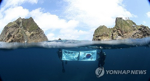 독도 일대를 조사 중인 한국해양과학기술원 울릉도독도해양연구기지 직원들이 광복절을 앞둔 지난 8월 14일 독도의 하늘과 바다를 배경으로 태극기를 펼쳐 보이고 있다. [울릉도독도해양연구기지 제공. 독도=연합뉴스]