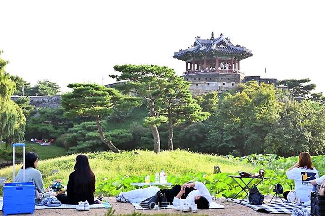 시민들이 수원화성 방화수류정이 보이는 용연에서 가을 피크닉을 즐기고 있다./사진-수원시