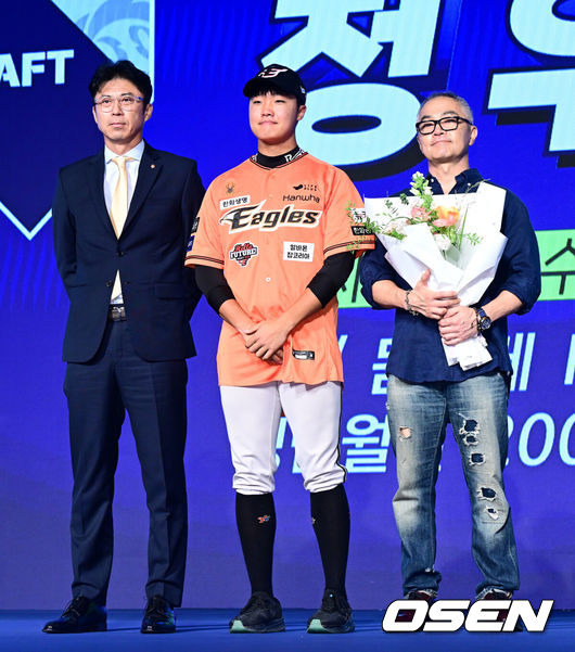 [OSEN=지형준 기자] 11일 오후 서울 잠실 롯데호텔 월드에서 2025 KBO 신인 드래프트가 열렸다.2025 KBO 신인 드래프트는 전면 드래프트 방식으로 진행된다. 지명은 1라운드부터 11라운드까지 이뤄지며, 2023년도 구단 순위의 역순인 키움-한화-삼성-롯데-KIA-두산-NC-SSG-KT-LG 순서로 실시된다.전주고 정우주가 한화에 지명되며 손혁 단장, 아버지와 포즈를 취하고 있다. 2024.09.11 / jpnews@osen.co.kr